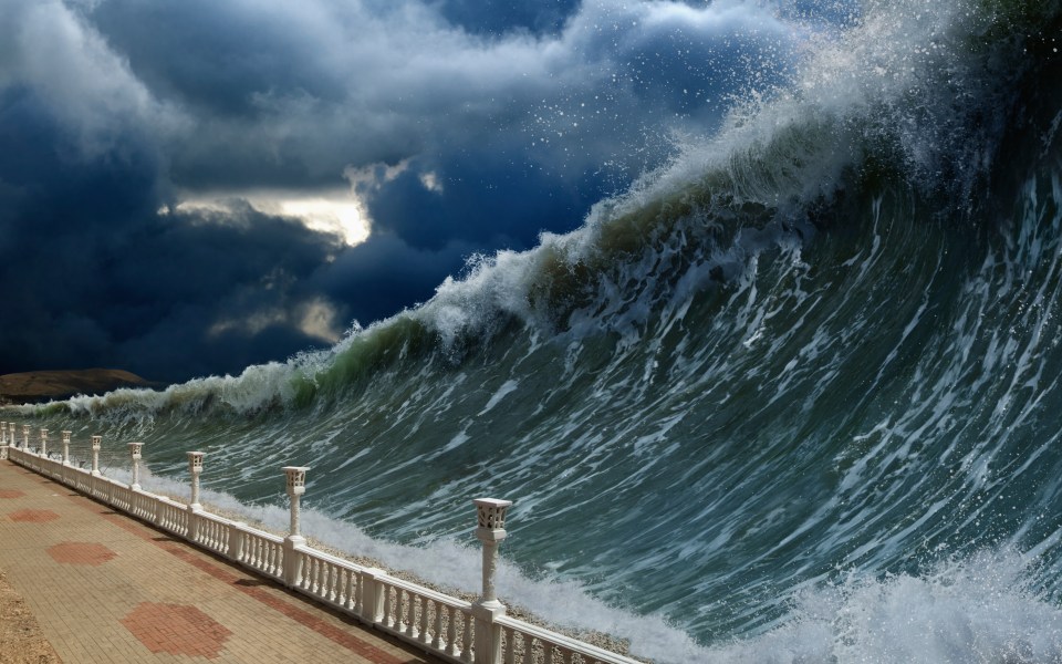 Uma enorme onda de tsunami prestes a atingir uma passarela costeira.