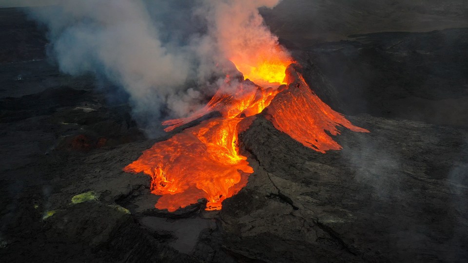 Vista aérea de um vulcão em erupção à noite.